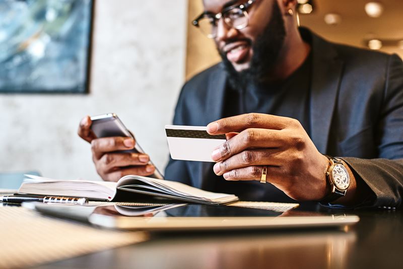 Man holding card while using phone