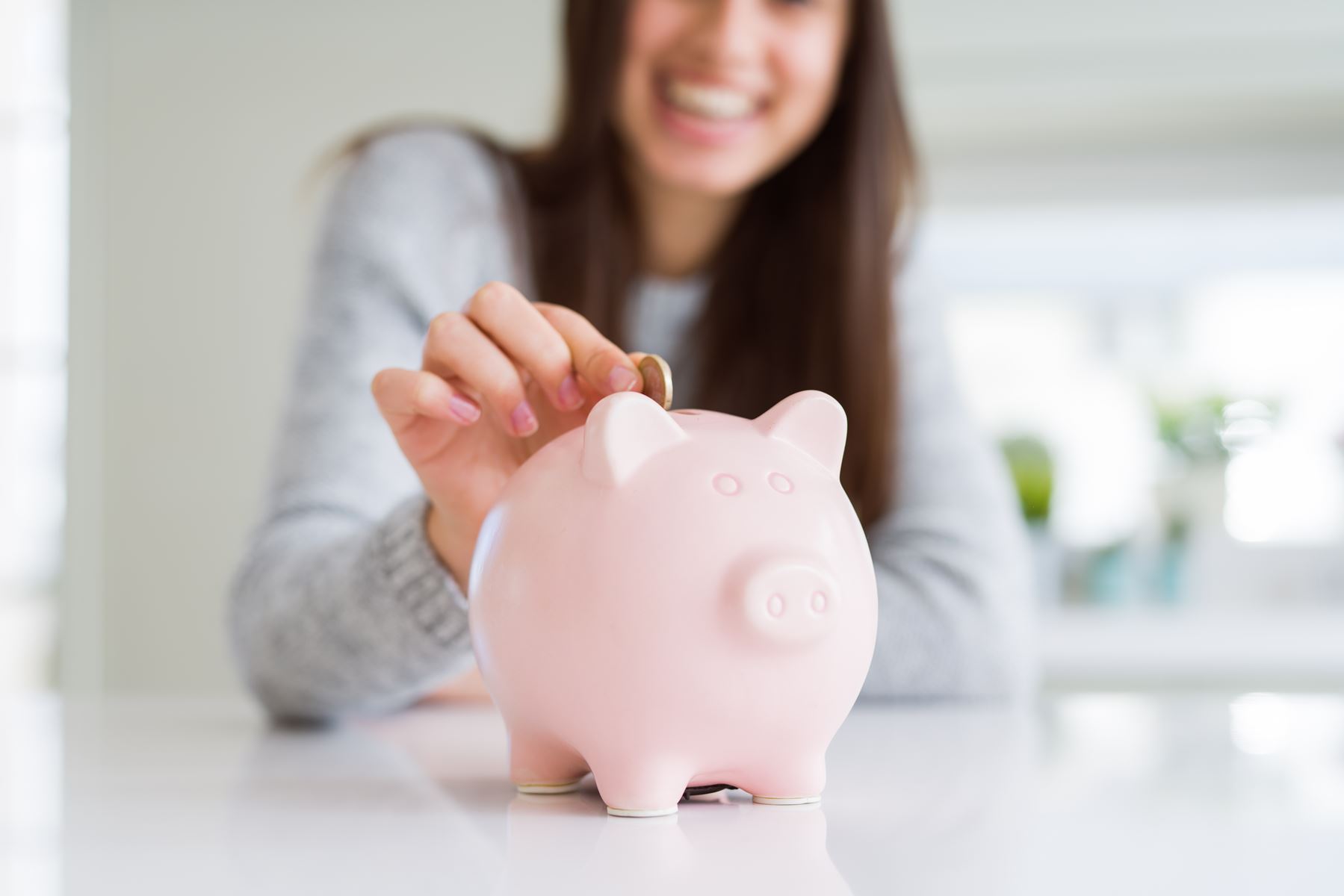 Woman putting coins in piggy bank